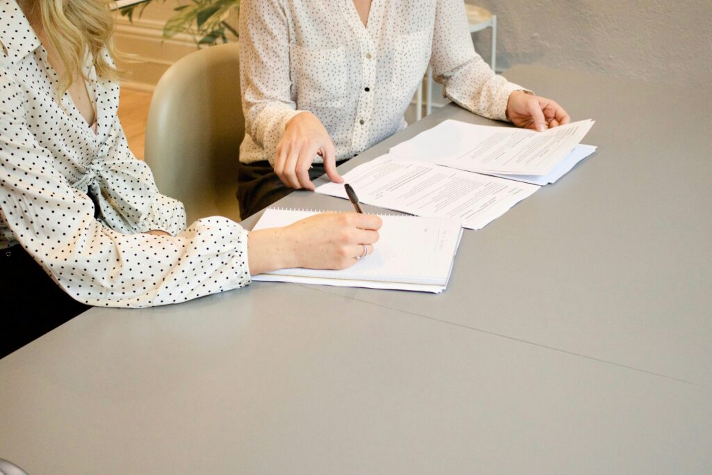 Close up of two people looking at papers on a desk.